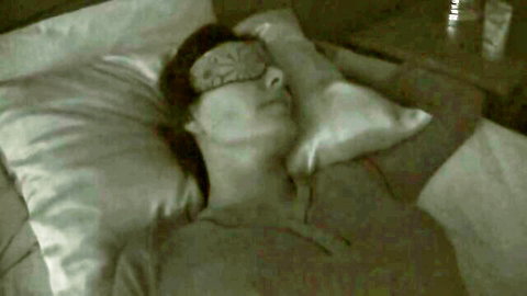 Blindfolded skinny MILF lying seductively on satin bed sheets with sleep mask