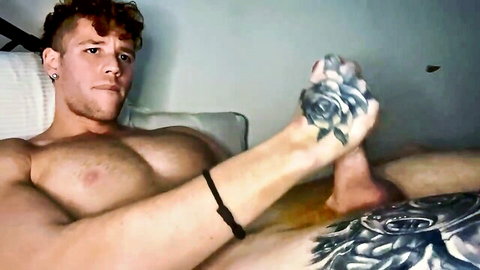 Muscular ginger hunk with rose tattoo spreads legs teasing on bed showing buff chest and thighs