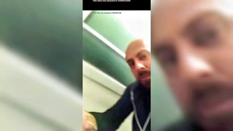 Blurry closeup of bald man in hoodie staring intensely in green tiled bathroom