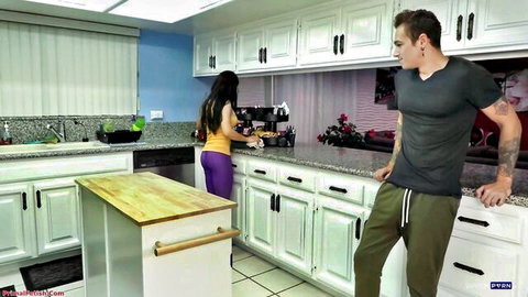 Curvy brunette MILF in tight purple leggings shows big ass to muscular stepson leaning on kitchen counter
