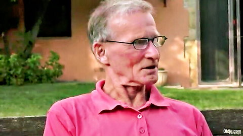 Old man with gray hair and glasses in pink polo shirt sitting outdoors on patio