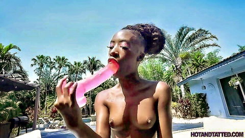 Petite black babe with small tits sucks huge pink dildo outdoors by pool