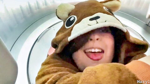 Cute girl in fluffy bear onesie stuck in washing machine sticks tongue out playfully