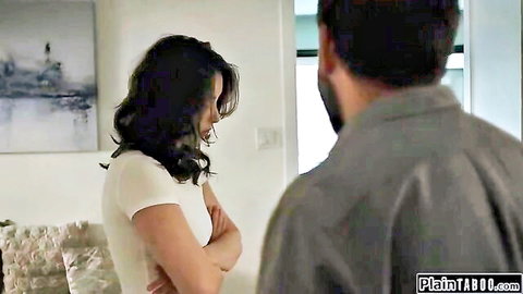 Brunette wife in white tee stands arms crossed as man approaches intimately