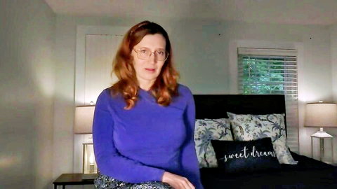 Bettie Bondage as curvy redhead MILF in purple sweater, glasses, seductive pose