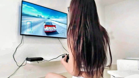Teen gamer girl with glasses in white panties squats playing racing game on TV