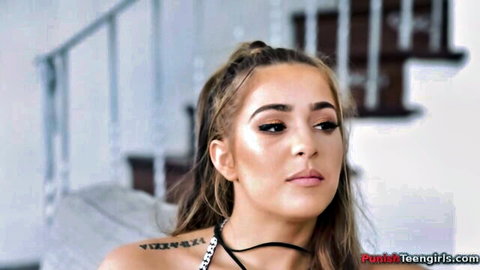 Petite teen girl with ponytail, choker necklace and shoulder tattoo looks seductive