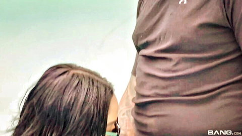 Brunette woman teasing muscular man's crotch at poolside party