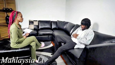 Malaysian teen in green outfit chats with BBC guy with dreads on couch