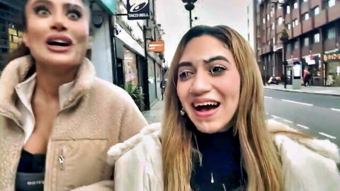 Two surprised women in fur coats walking excitedly on public urban street