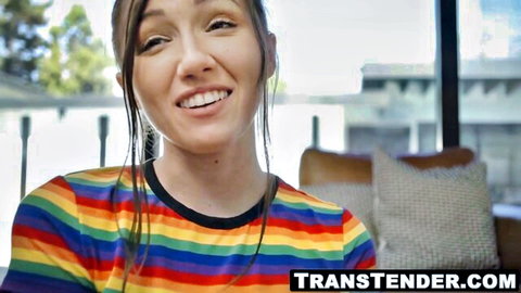 Smiling young trans brunette in rainbow shirt teasing viewers