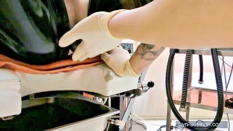 Latex-gloved femdom mistress fingers exposed pussy of bound slave in gyno exam chair