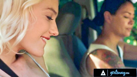 Blonde Kenna James smiles intimately with tattooed Dana Vespoli in car