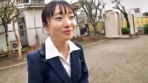 Clothed Asian teacher in navy suit smiling in schoolyard outdoors