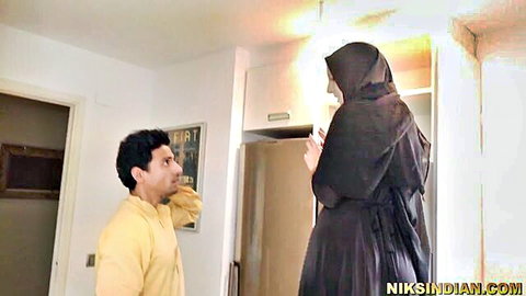 Indian man in kurta seduces tall veiled Arab woman in black abaya in kitchen