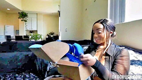 Ebony teen in sheer top excitedly unboxes blue lingerie smiling seductively