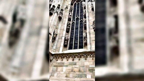 Gothic cathedral facade with tall stained glass windows and intricate stone carvings towering above