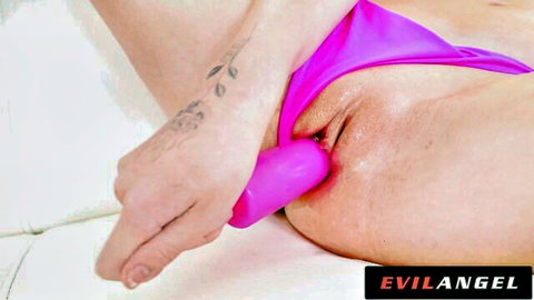 Tattooed babe pulls aside pink thong to insert thick pink dildo into her wet pussy