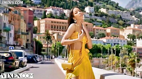 Lia Lin in yellow summer dress on sunny coastal street, stunning pose