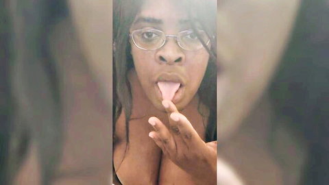 Ebony babe with glasses sticks out tongue, teasing deep cleavage in seductive selfie