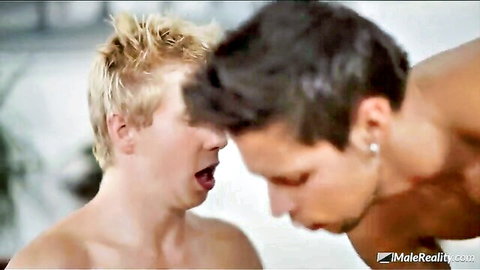 Blonde twink giving blowjob to muscular dark-haired guy in safe sex scene