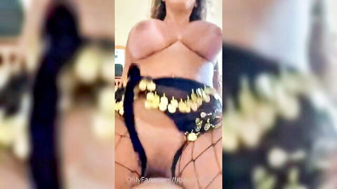 Blonde vixen in skimpy belly dance belt and fishnets, exposing big tits and pussy