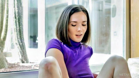 Eve Sweet teases in purple top with legs spread, soft sunset glow