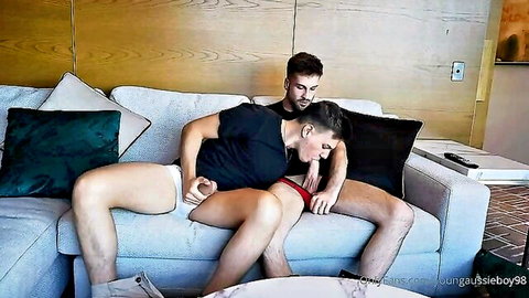 Muscular gay couple in explicit intimate pose, one exposing genitals