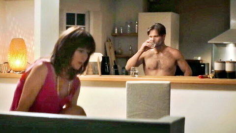 Sophie Marceau in pink top with shirtless muscular man in intimate kitchen moment