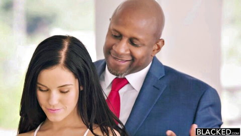 Petite brunette in white dress stands with smiling bald BBC in suit behind her