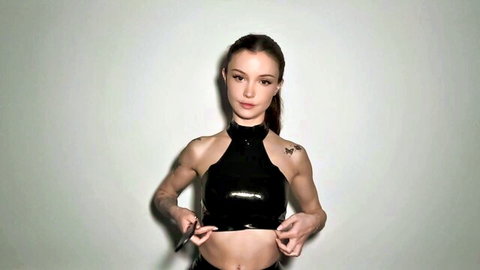 Dainty Wilder in shiny black latex top, seductive femdom pose with ponytail