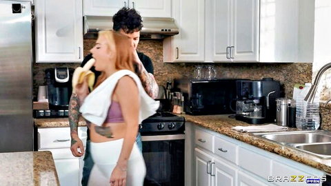 Cubbi Thompson teases with banana in mouth, man behind in kitchen