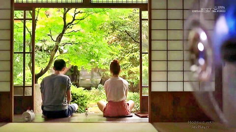 Serene Japanese couple in casual clothes relaxing by garden window