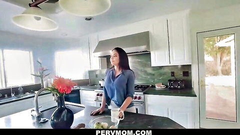 Brunette MILF in blue blouse posing seductively at kitchen counter with coffee mug