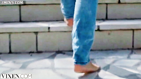 Barefoot woman in tight blue jeans walking up concrete stairs