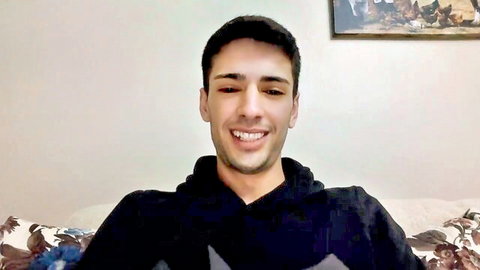 Handsome young Latino man smiling seductively in hoodie, gay solo tease