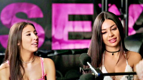 Two tattooed brunettes in pink outfits chatting on Rocco Siffredi's sex set
