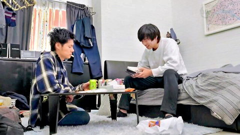 Two slim Japanese guys in casual clothes sharing a book intimately