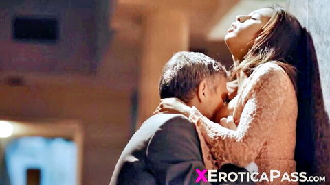 Suited man passionately kissing busty brunette's huge cleavage tits in sensual embrace