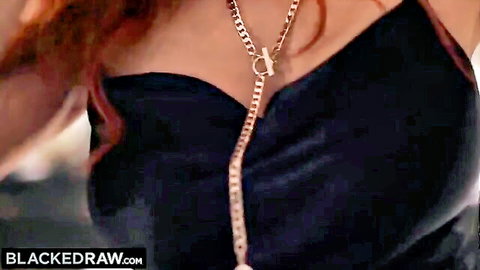Seductive redhead in black satin dress with chain necklace accentuating cleavage