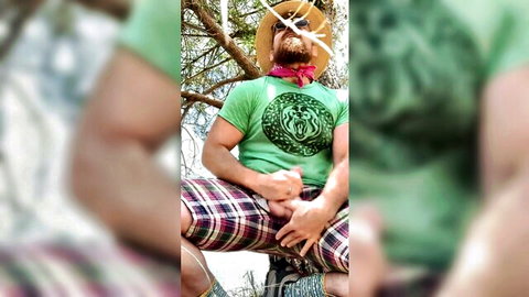 Bearded muscular man outdoors grips his thick erect cock bulging from open plaid shorts in solo exposure