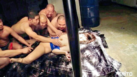 Naked Japanese woman surrounded by muscular Asian men groping her tits and pussy in intense gangbang.