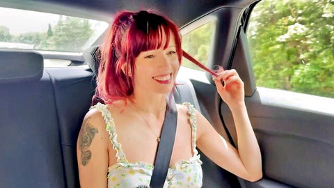 Chaarlene Savors smiles in car with red hair and arm tattoo, light dress