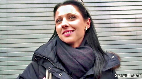 Smiling brunette woman in puffy jacket and scarf posing outdoors for casting