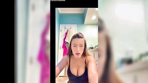 Brunette webcam babe teases deep cleavage with huge tits in tight black tank top bathroom selfie