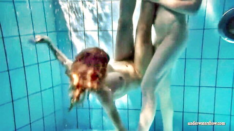 Nude redhead upside down underwater in pool with legs spread exposing wet pussy held by naked lesbian partner
