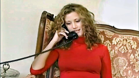 Mature curly-haired woman in red turtleneck on phone call
