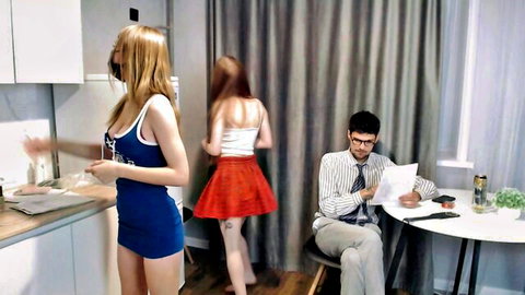 Blonde in blue tank top and mini skirt teases suited man while redhead in white top and red skirt stands nearby in kitchen