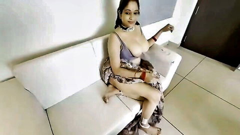 Busty Indian babe with massive tits spilling from low-cut purple top and sheer saree teasing on sofa