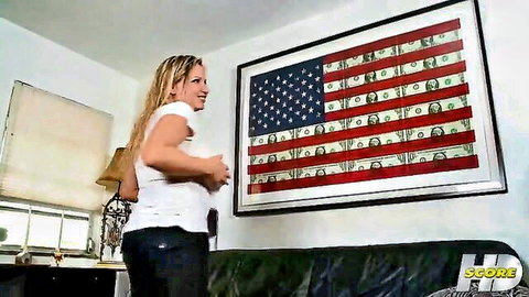 Blonde MILF squeezing her big tits in tight white top before money-faced American flag